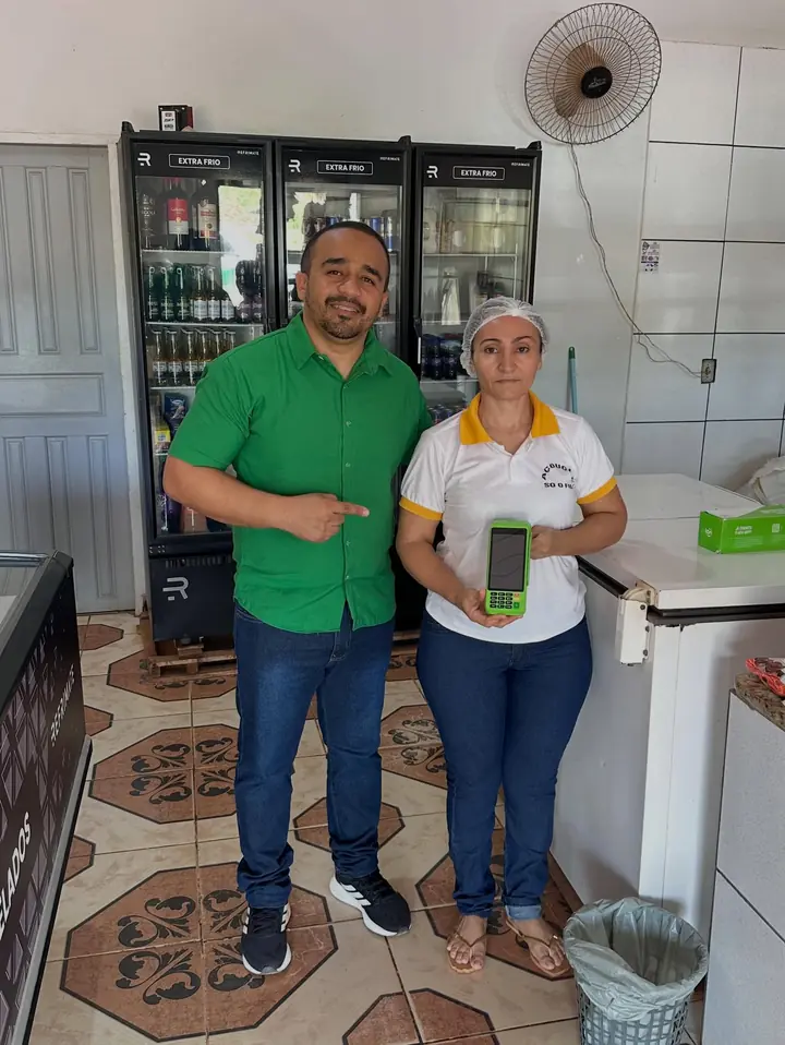 Bruno ao lado de uma comerciante que recebeu sua maquininha