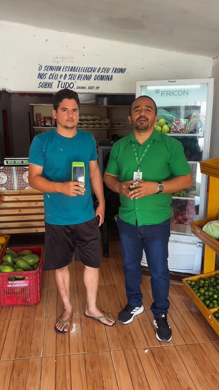 Bruno ao lado de um comerciante segurando uma maquininha Ton